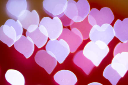 Background of different colors defocused lights with a heart shape on a red background. Abstract image. Valentine, love and passion conceptの写真素材