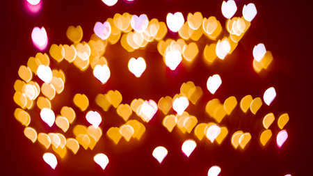Background of different colors defocused lights with a heart shape on a red background. Abstract image. Valentine, love and passion conceptの写真素材