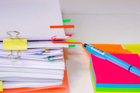 Close-up of a pile of paper with colored post its and a pen. Information overload conceptClose-up of...