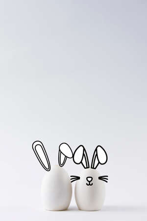 Close-up of some white eggs on white background with bunny ears. Easter bunny concept with bunny earsの写真素材