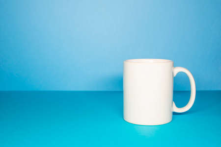 Mock up of a white mug on a blue background. Template for corporate materialの写真素材