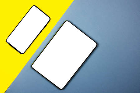 Mock up of a smartphone and a tablet on different colored backgrounds.の写真素材