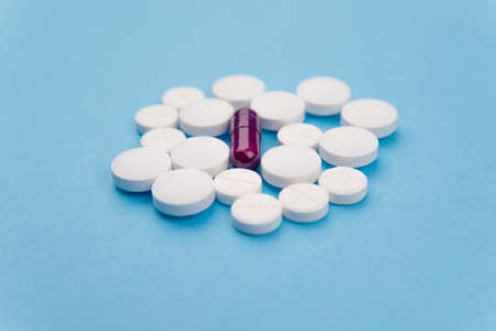 Overhead shot of several white pills and a purple one. Concept of drugs for the treatment of diseasesの写真素材