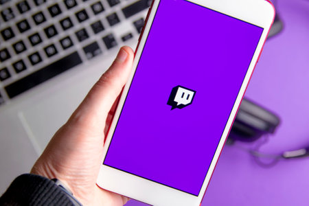 Spain. 03, 05, 2021. Closeup of smartphone screen with logo lettering of video live streaming platform twitch on computer keyboardのeditorial素材