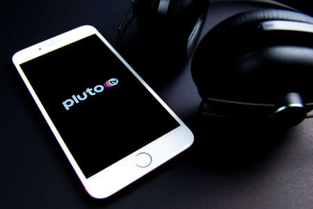 Spain. 03, 05, 2021. Pluto TV app icon in an Iphone with eardphones. Pluto TV is a free live-stream television and on-demand video service from ViacomCBS.のeditorial素材