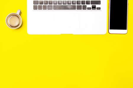 Teleworking workspace. Laptop, coffee and smartphone on yellow backgroundの写真素材