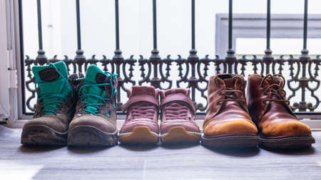 Shoes of two men and a girl on a balcony door. Family everyday life concept. Gay families, two fathers. World family dayの写真素材