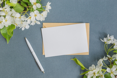 Mockup white greeting card and envelope with white spring flowers and dark backgroundの写真素材