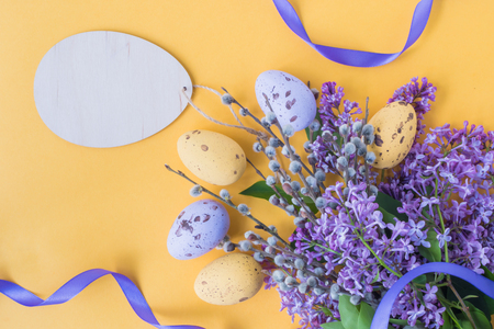 Easter eggs and lilac branches on a yellow backgroundの写真素材