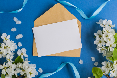 Mockup white greeting card and envelope with white spring flowers and blue backgroundの写真素材