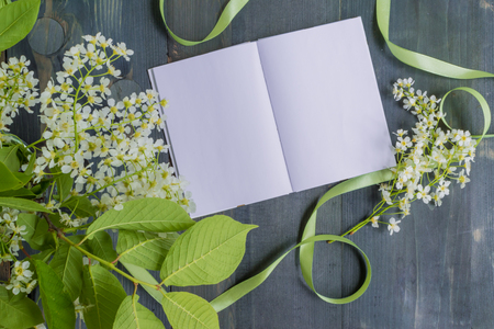 Mockup notebook with white spring flowers and rustic wooden background empty space for your text, top viewの写真素材