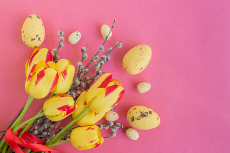 Easter eggs willow branches and yellow tulips on a pink backgroundの写真素材