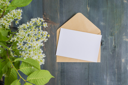 Mockup white greeting card and envelope with white spring flowers and rustic wooden backgroundの写真素材