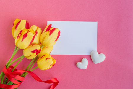 Mockup white greeting card with yellow tulips flowers and pink backgroundの写真素材