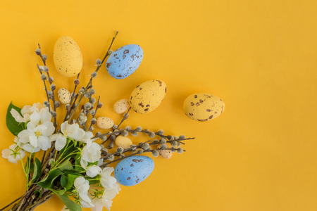 Easter eggs willow branches and white spring flowers on a yellow backgroundの写真素材