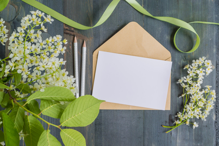 Mockup white greeting card and envelope with white spring flowers and rustic wooden backgroundの写真素材