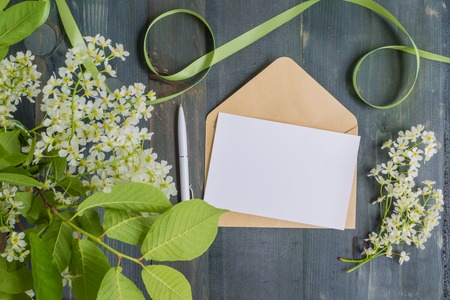 Mockup white greeting card and envelope with white spring flowers and rustic wooden backgroundの写真素材