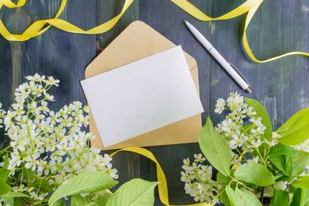 Mockup white greeting card and envelope with white spring flowers and rustic wooden backgroundの写真素材