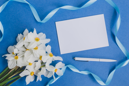 Mockup white greeting card with white daffodils flowers and blue backgroundの写真素材