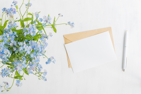 Mockup white greeting card and envelope with blue flowers and light backgroundの写真素材