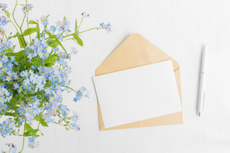 Mockup white greeting card and envelope with blue flowers and light backgroundの写真素材