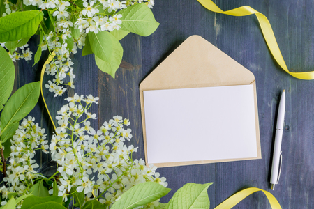 Mockup white greeting card and envelope with white spring flowers and rustic wooden backgroundの写真素材