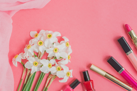 Flat lay desk with white daffodils,  ribbon and cosmetic on pink backgroundの写真素材