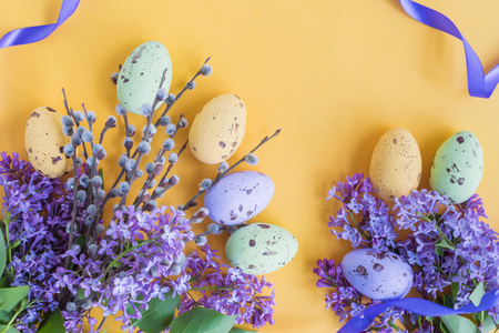 Easter eggs and lilac branches on a yellow backgroundの写真素材
