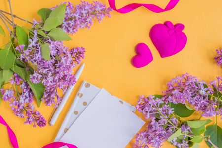 Flat lay desk with lilac branches and notebook on yellow backgroundの写真素材