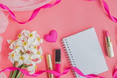 Flat lay desk with notebook and cosmetic on pink backgroundの写真素材