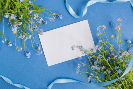 Mockup white greeting card with blue flowers and blue backgroundの写真素材