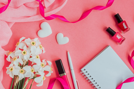 Flat lay desk with notebook and cosmetic on pink backgroundの写真素材
