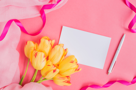 Mockup white greeting card with yellow tulips flowers and pink backgroundの写真素材