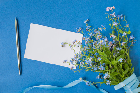Mockup white greeting card with blue flowers and blue backgroundの写真素材