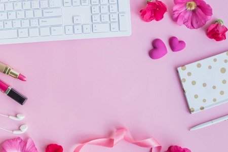 Blogger or freelancer workspace with notebook and pink flowers on pink backgroundの写真素材