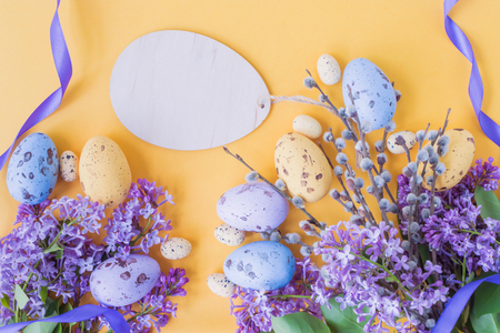 Easter eggs and lilac branches on a yellow backgroundの写真素材