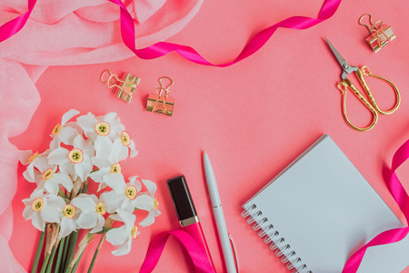 Flat lay desk with notebook and cosmetic on pink backgroundの写真素材
