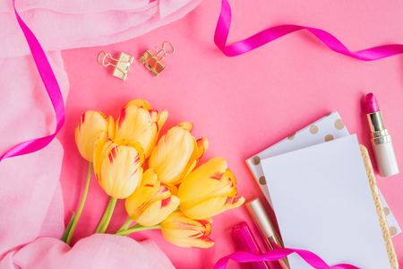 Flat lay desk with notebook and cosmetic on pink backgroundの写真素材