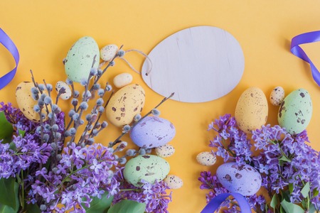 Easter eggs and lilac branches on a yellow backgroundの写真素材