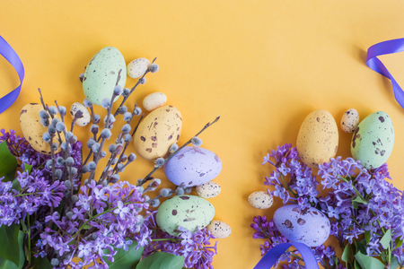 Easter eggs and lilac branches on a yellow backgroundの写真素材