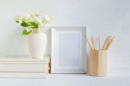 Home interior with decor elements. White frame, flowers in a vase, books and pencilsの写真素材