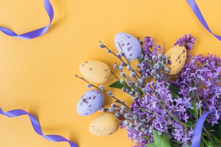 Easter eggs and lilac branches on a yellow backgroundの写真素材