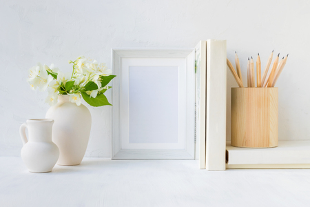 Home interior with decor elements. White frame, flowers in a vase, books and pencilsの写真素材