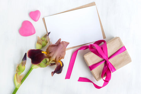 Mockup white greeting card and gift box with iris flowers and light backgroundの写真素材