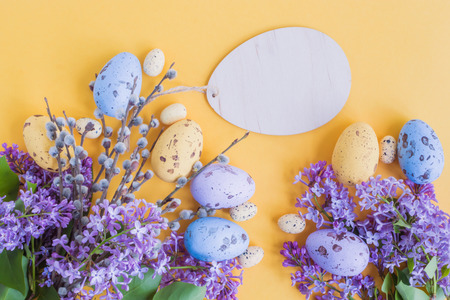 Easter eggs and lilac branches on a yellow backgroundの写真素材