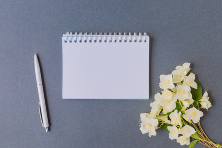 Mockup notebook with white jasmine flowers and dark background empty space for your text, top viewの写真素材