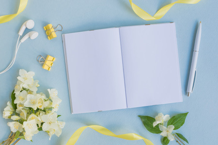 Mockup notebook with white jasmine flowers and light blue background  empty space for your text, top viewの写真素材