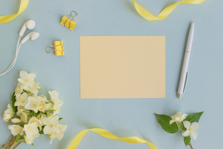 Mockup light yellow greeting card with white jasmine flowers and light blue backgroundの写真素材