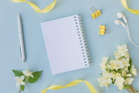 Mockup notebook with white jasmine flowers and light blue background  empty space for your text, top viewの写真素材