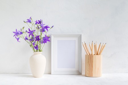 Home interior with decor elements. White frame, flowers in a vase, pencilsの写真素材